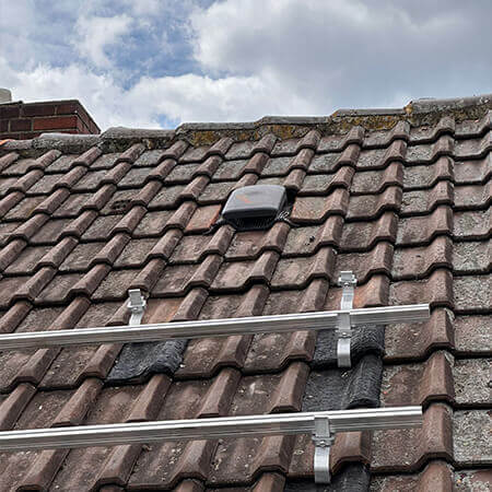 Flachl&uuml;fter auf einem Dach, damit ein Photovoltaikmodul dar&uuml;ber montiert werden kann und Modultragschienen und Dachhaken